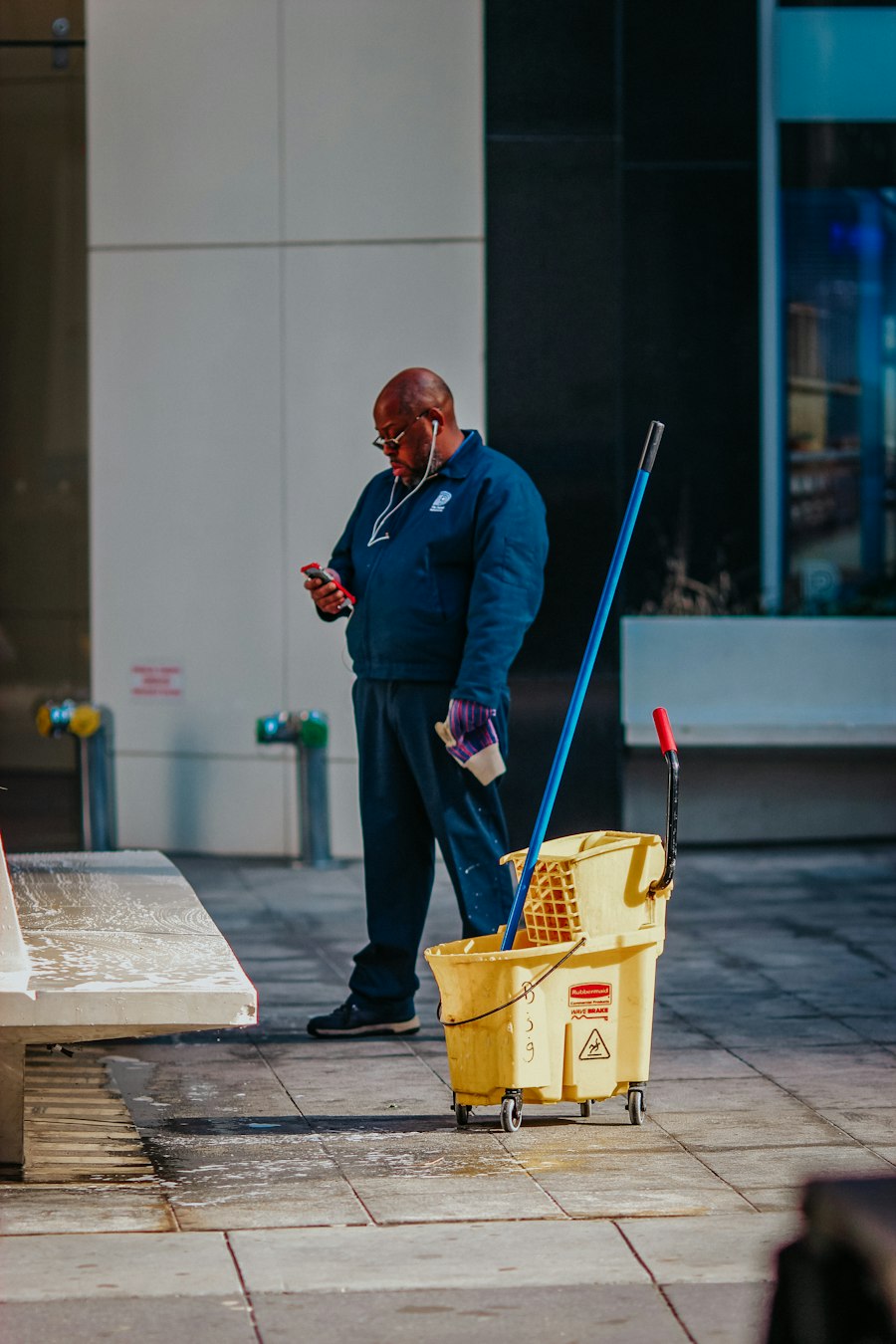 Cleaning crew member with mop and bucket at a building entrance