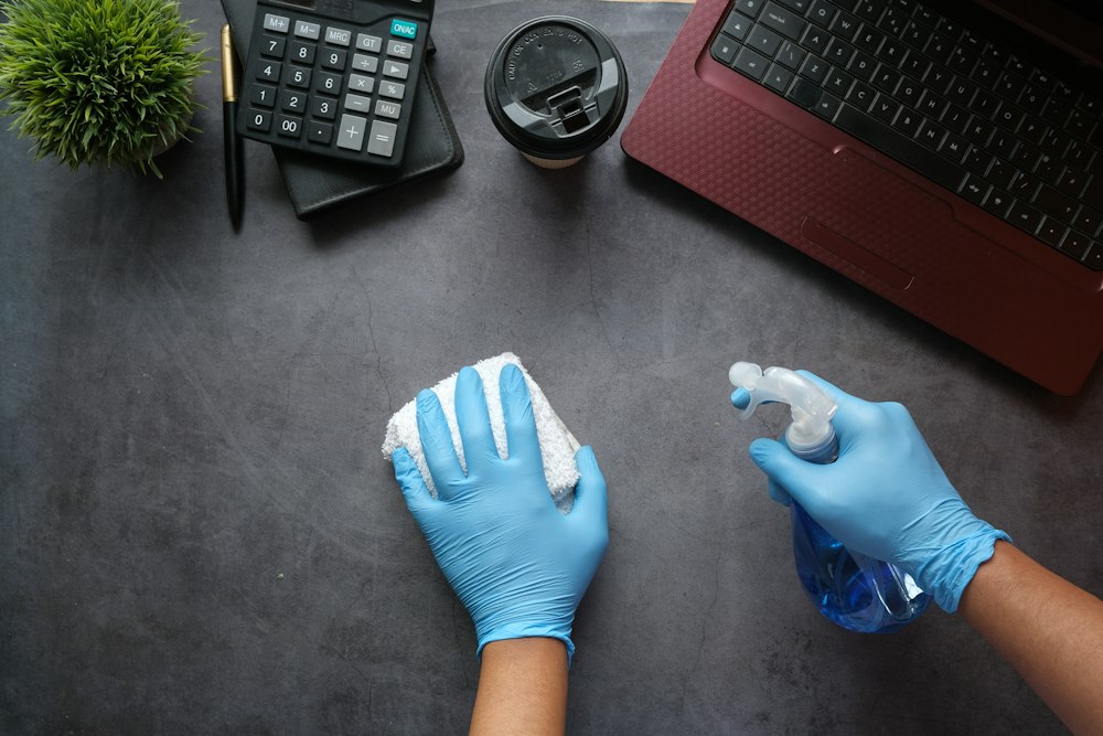 Technician disinfecting an office desk and keyboard